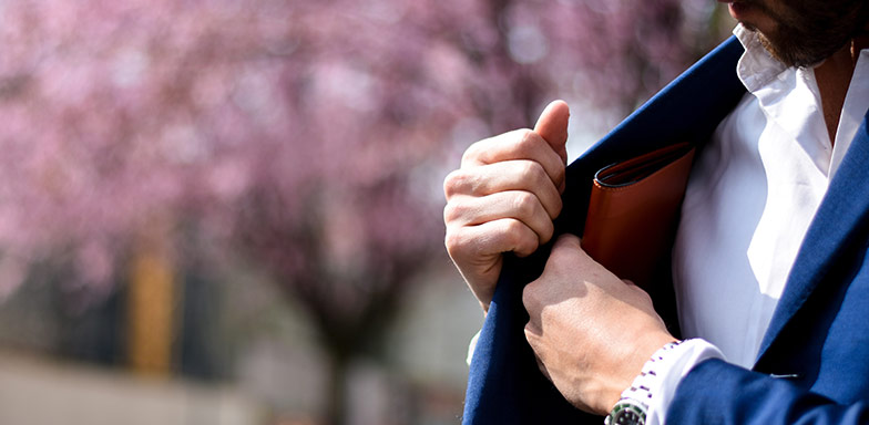 A man putting a folder inside his inner jacket pocket.