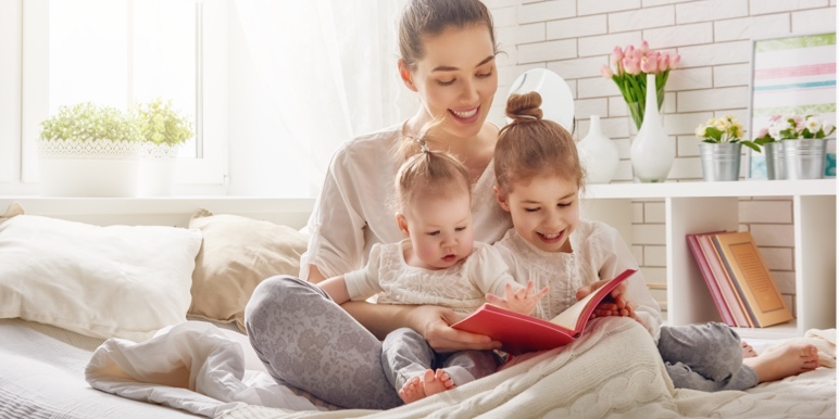 A young woman reading a book to her two toddlers