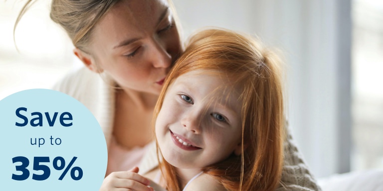 Mom kisses her young daughter on her head.