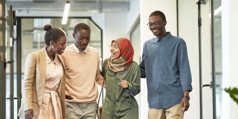 A group of 4 individuals walking and chatting about the advantages of employee benefits from Momentum Corporate.