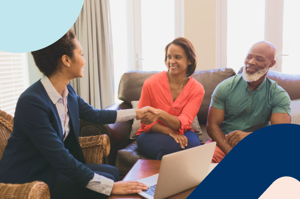 A momentum financial adviser meeting with an elder couple at home, shaking hands and offering professional guidance.