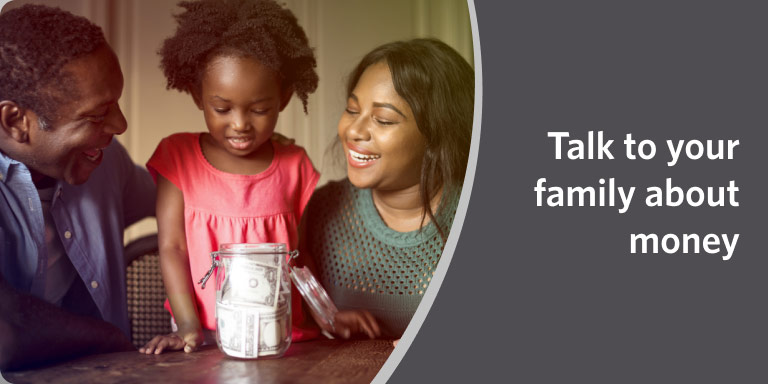 Smiling parents and young daughter placing coins in a jar in a video about discussing money with family.