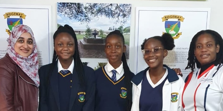 A portrait photograph taken of four schoolgirls and their teacher wearing a hijab.
