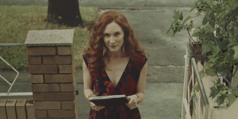 A young woman called Alice walking up a flight of stairs holding a book.