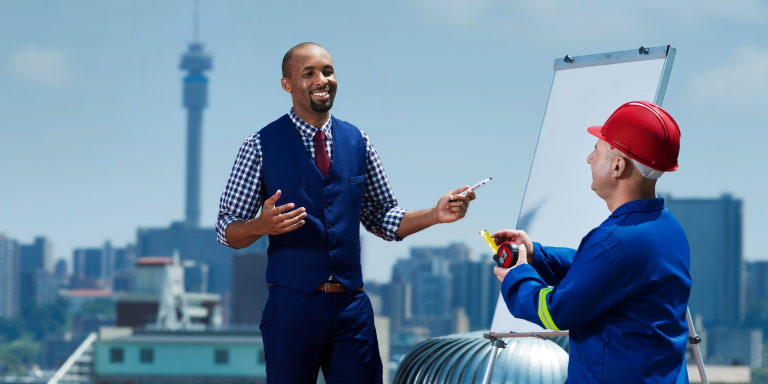 A construction worker on site, attending an educational course with a lecturer using his Group Insurance employee  benefits.