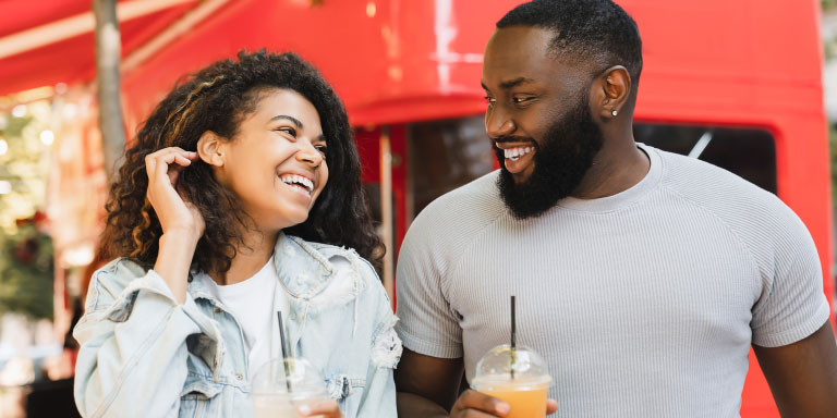 A young female and male holding smoothies chatting about the Ingwe Option from Momentum Medical Scheme that's suitable for first time earners and students.