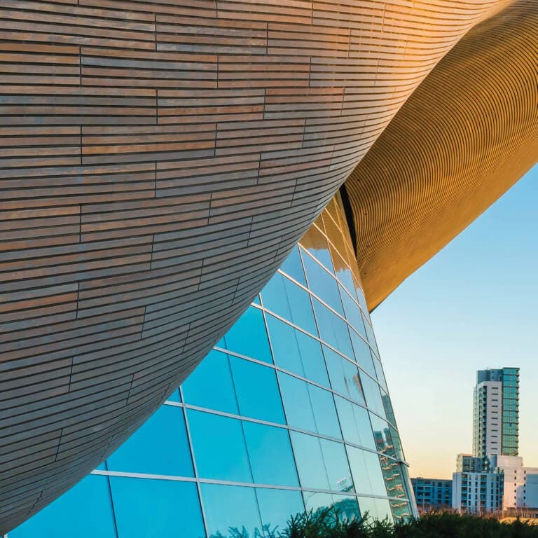 A futuristic, round, glass and steel office building with an abstract and asymmetric curved roof.