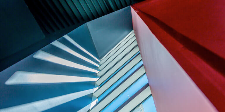 A descending flight of stairs with a red wall on one side and a blue wall on the other.