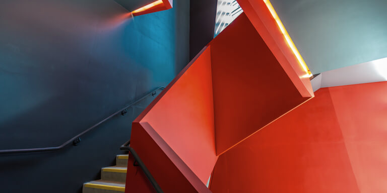 A staircase in a modern office building with an abstract, red and geometric balustrade.