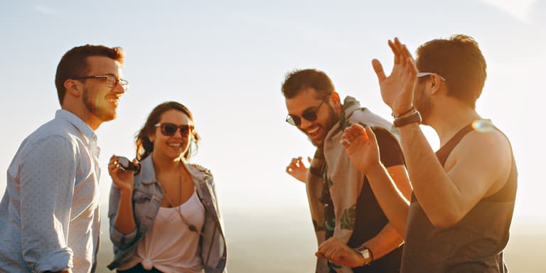 A group of three guys and a lady dancing and having fun in the afternoon sun.