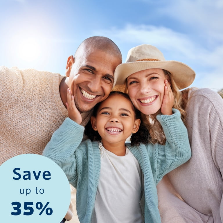 Parents enjoy a day outdoors with their young daughter. The daughter is standing in the middle of them with her hands on each parent's cheeks.