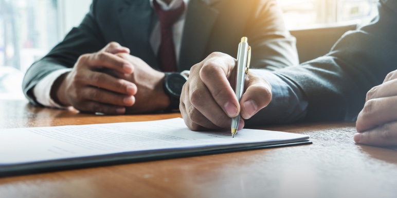 A man signing a Wills document in front of a witness.