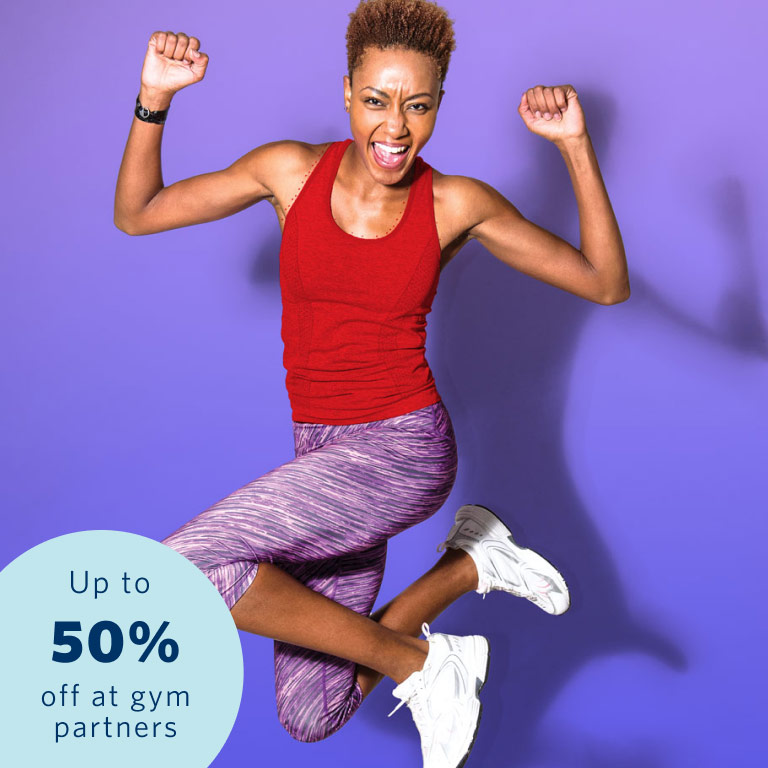 An athletic lady in a red sleeveless top and purple training pants jumping up as she reached her fitness goals with Momentum Multiply.