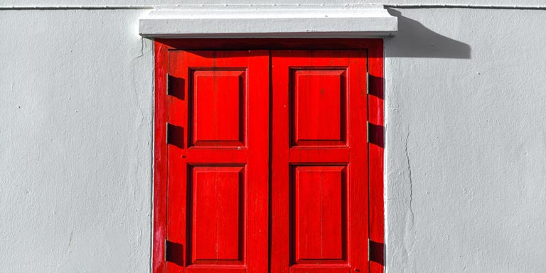 A gray building with a red wooden door.