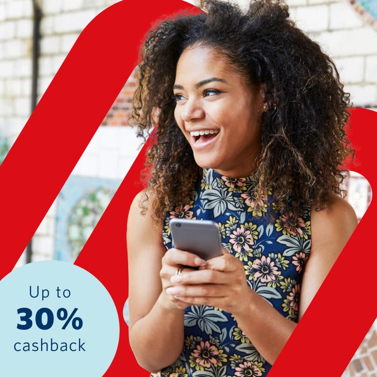 Young lady with a blue floral top holding a cell phone in her hands smiling as she discovered she can earn up to 30% of paid premiums back in cash every year, even if you claim, at no additional cost.