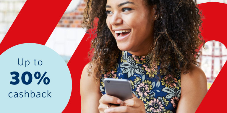 Young lady with a blue floral top holding a cell phone in her hands smiling as she discovered she can earn up to 30% of paid premiums back in cash every year, even if you claim, at no additional cost.