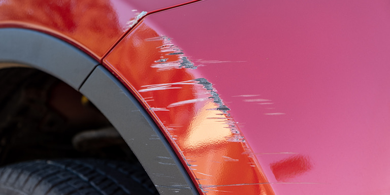 Scratches on a red car above the wheel.