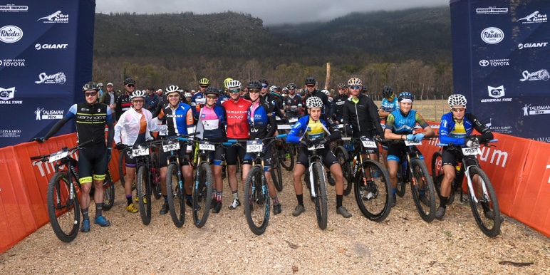 A group of cyclists pictured with the Momentum logo in the background cycle