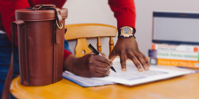 Man wearing a red cardigan gathering his paperwork to submit to TaxTim.