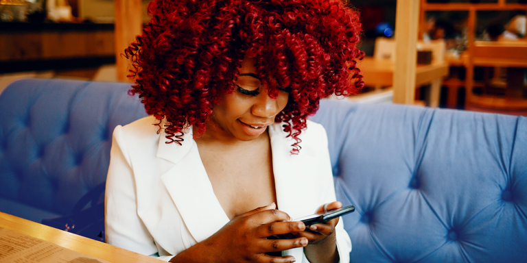 Woman in a smart white jacket submitting her tax return to TaxTim on her cell phone.
