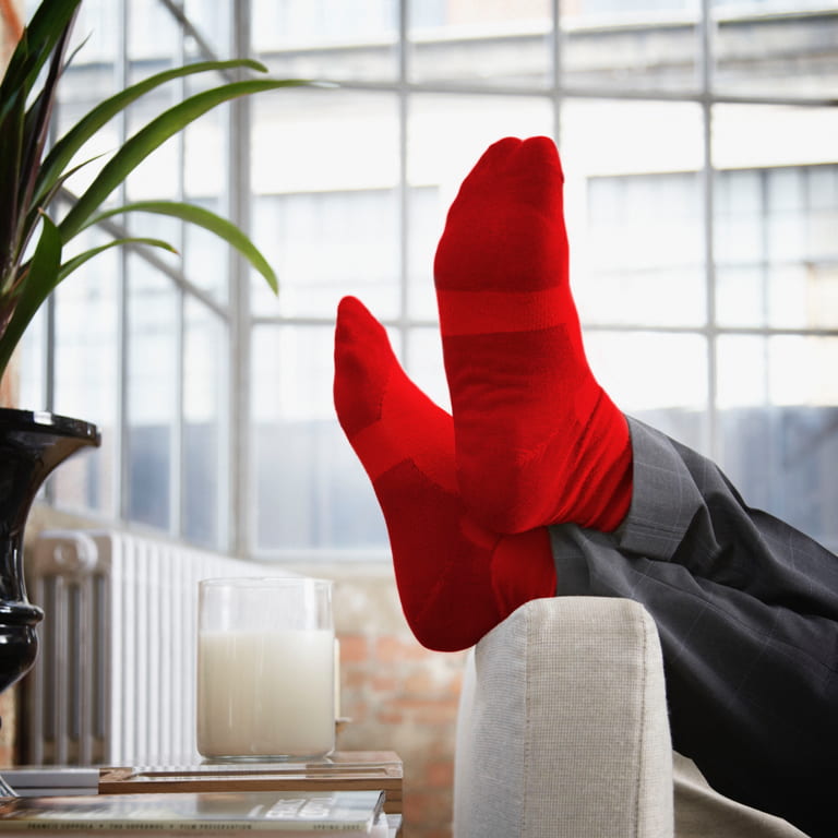 Relaxed feet in red socks on a couch with a glass of milk on the side table.