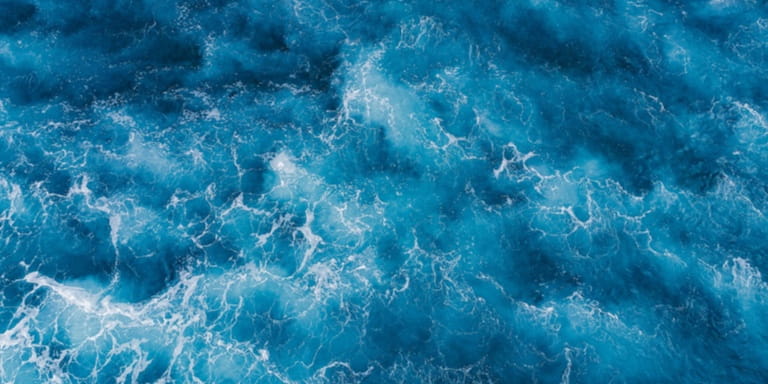An aerial view of rough, deep blue sea water.
