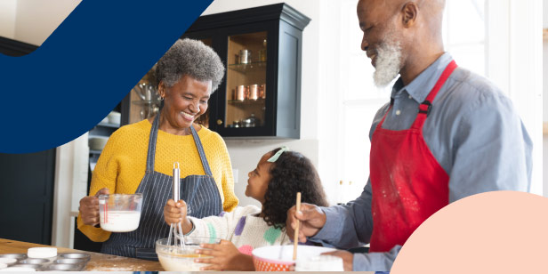 A retired couple in the kitchen teaching their granddaughter how to bake by mixing ingredients in different baking bowls.