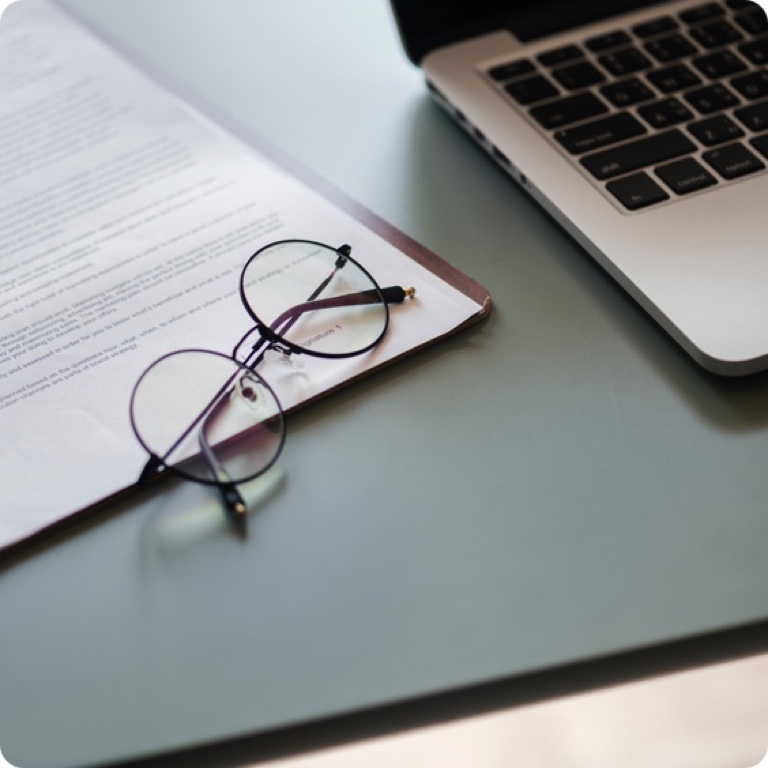 Reading glasses placed on an unsigned Will document with a pen next to it and an open laptop.