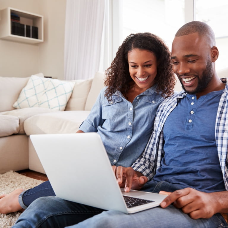 Young couple sitting on the floor of their living room, drafting their Will as part of the estate planning process.