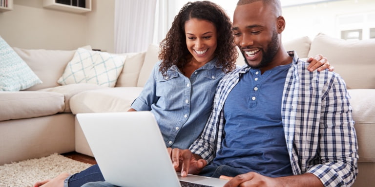 Young couple sitting on the floor of their living room, drafting their Will as part of the estate planning process