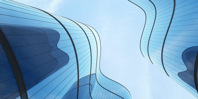 Low-angle view of 2 curved glass buildings reflecting off each other.