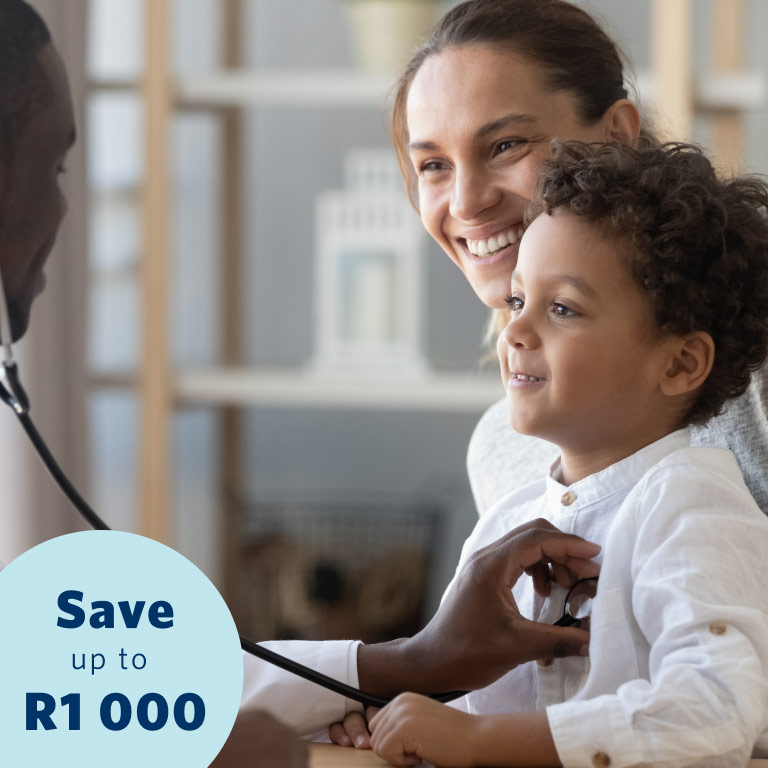 A content little boy sitting on his mother’s lap gets his chest examined by a young male doctor using a stethoscope.